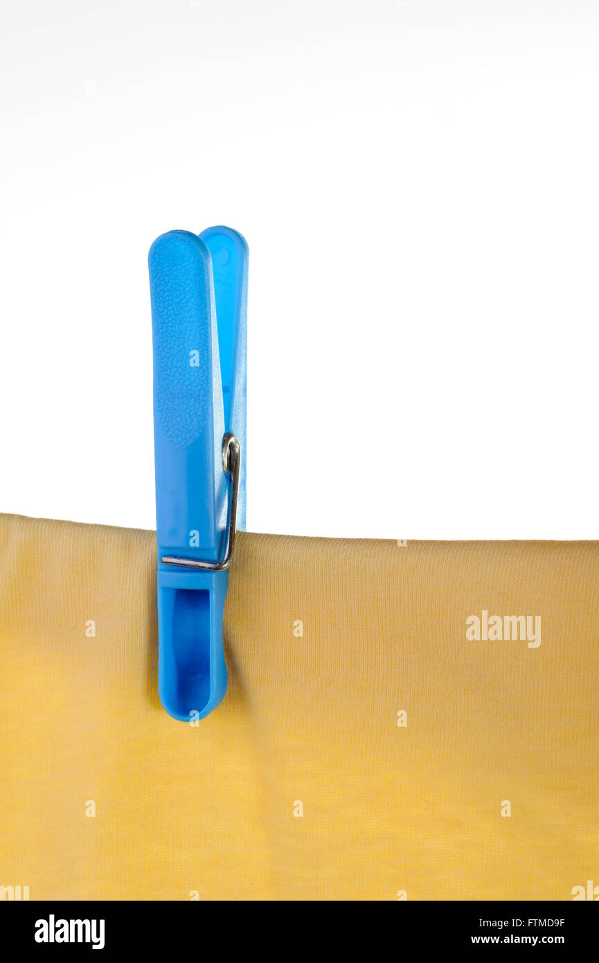 Blue plastic clothes peg or pin securing a yellow t-shirt on clothes line. Stock Photo