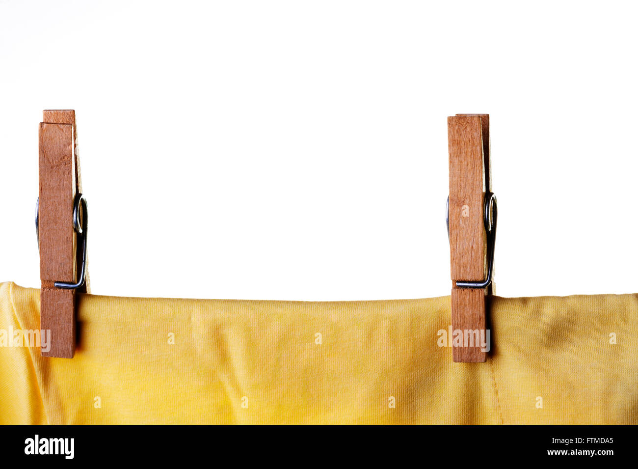 Wooden clothes peg or pin securing a yellow t-shirt on clothes line. Stock Photo