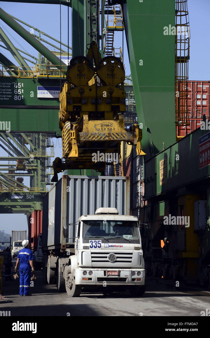 Workman overseeing removal of container from truck to ship loading Stock Photo