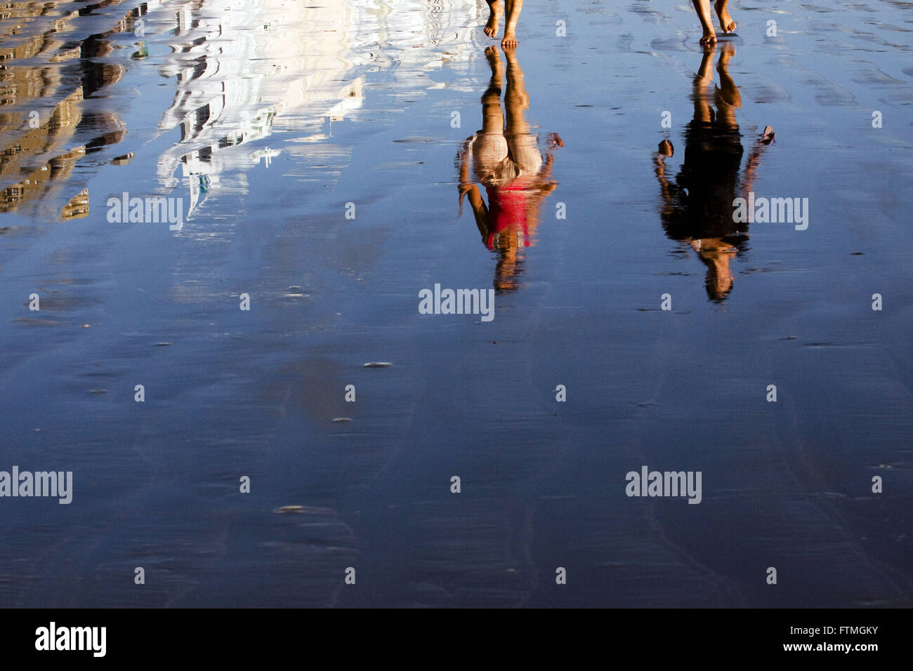 Reflection of bathers walking on the beach in Balneario Camboriu Stock Photo