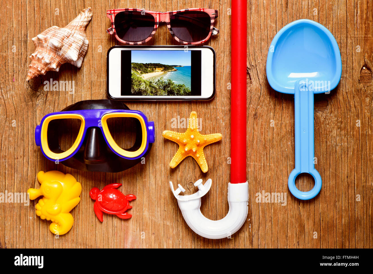 a rustic wooden table full of summer stuff, such a pair of sunglasses, a starfish, a conch, a diving mask or a snorkel, and a sm Stock Photo