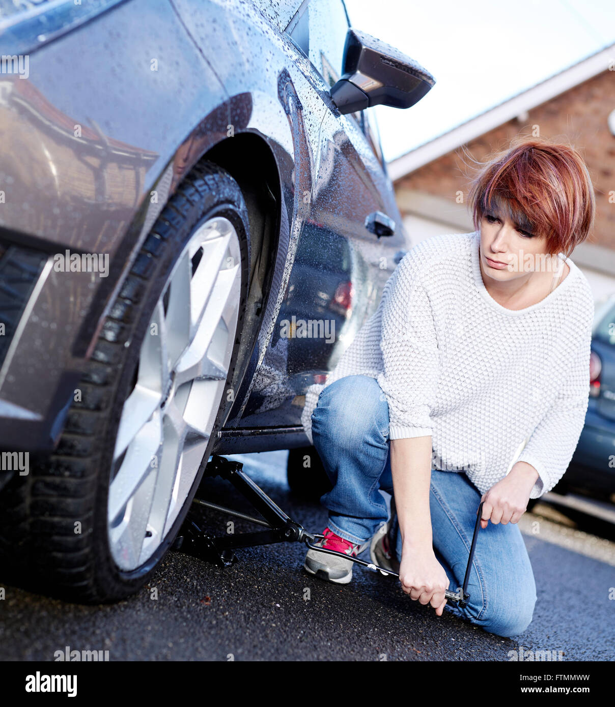 Woman changing wheel on her car Stock Photo