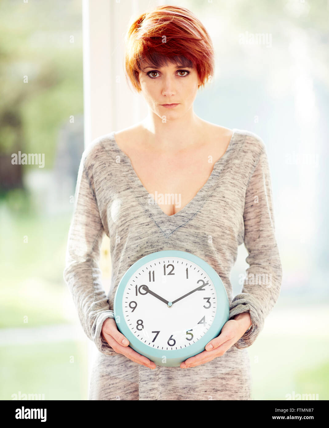 Woman stood holding a clock Stock Photo