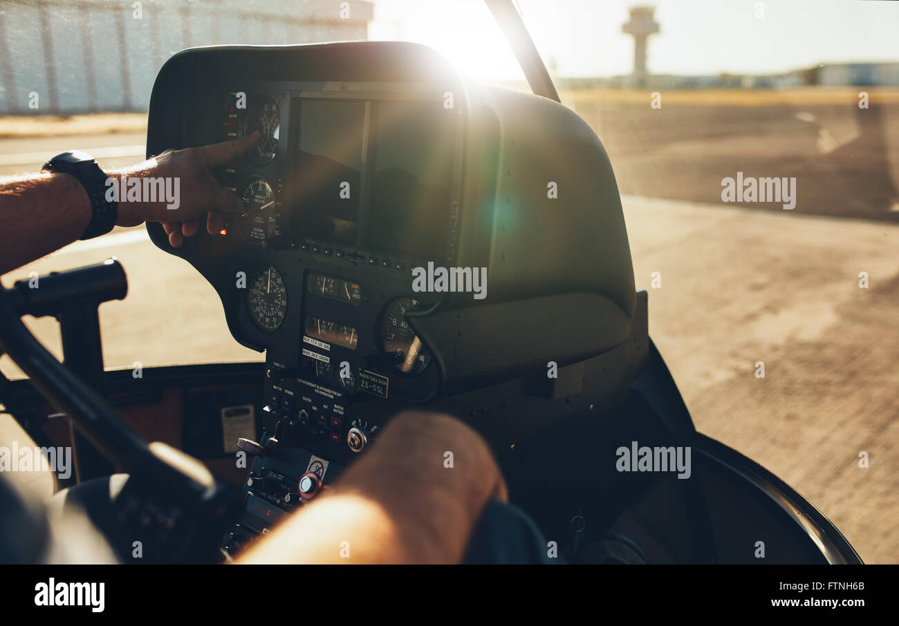 Close up shot of pilot checking the gauges on the instrument panel dashboard of  a helicopter with bright sunlight. Stock Photo