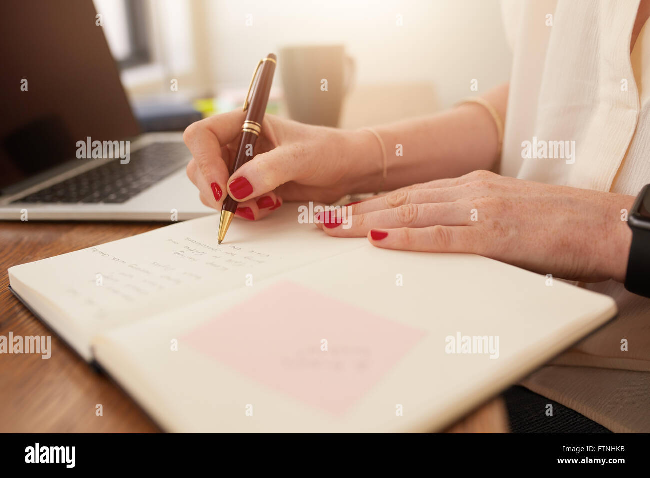 Close up image of woman writing notes in her diary. Businesswoman sitting at her desk and taking important notes in her personal Stock Photo