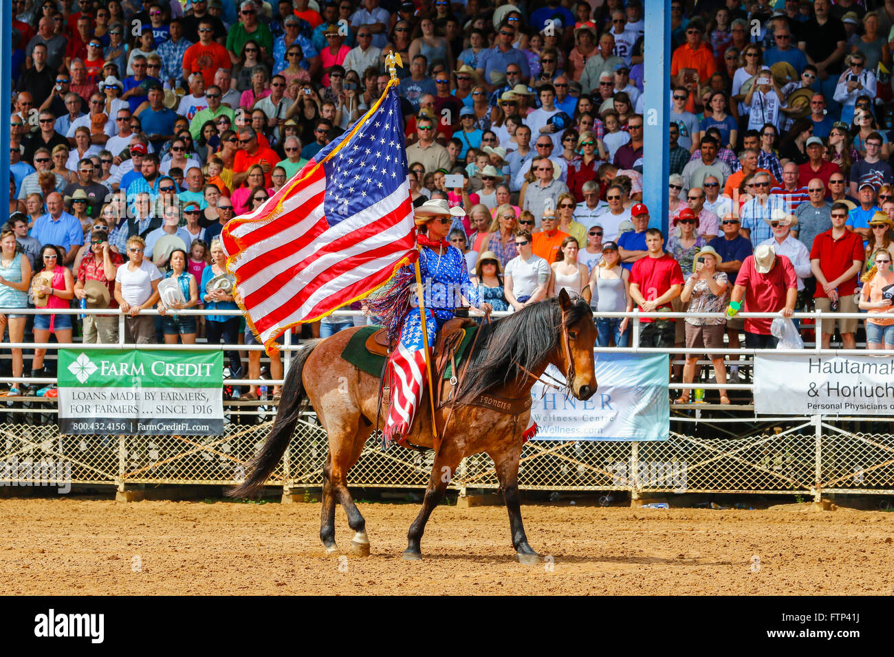 Woman horse riding and parading the national flag of USA around the