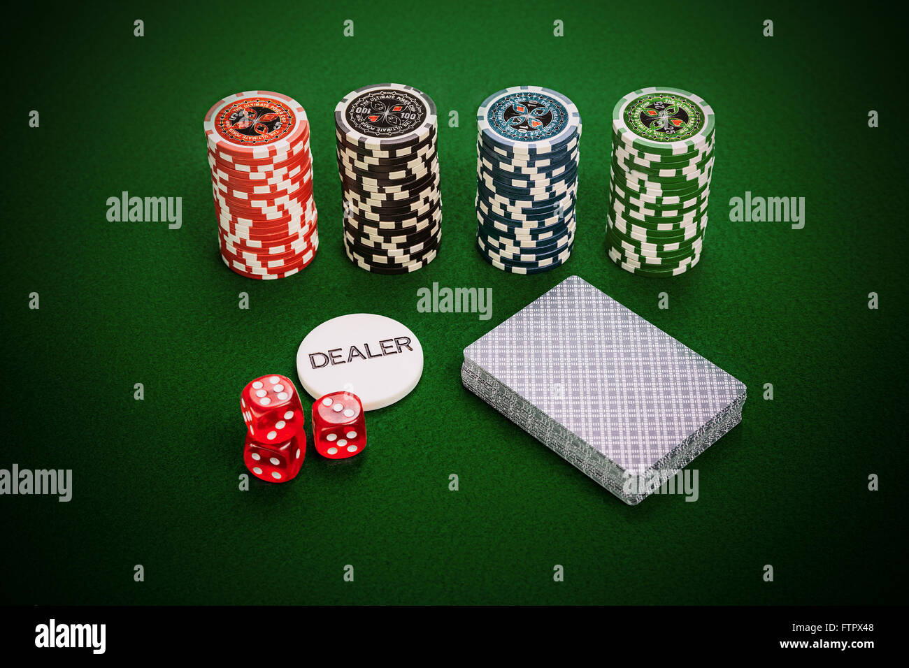 Casino chips, deck of cards, dealer chip and red casino dices lying on green casino table. Stock Photo