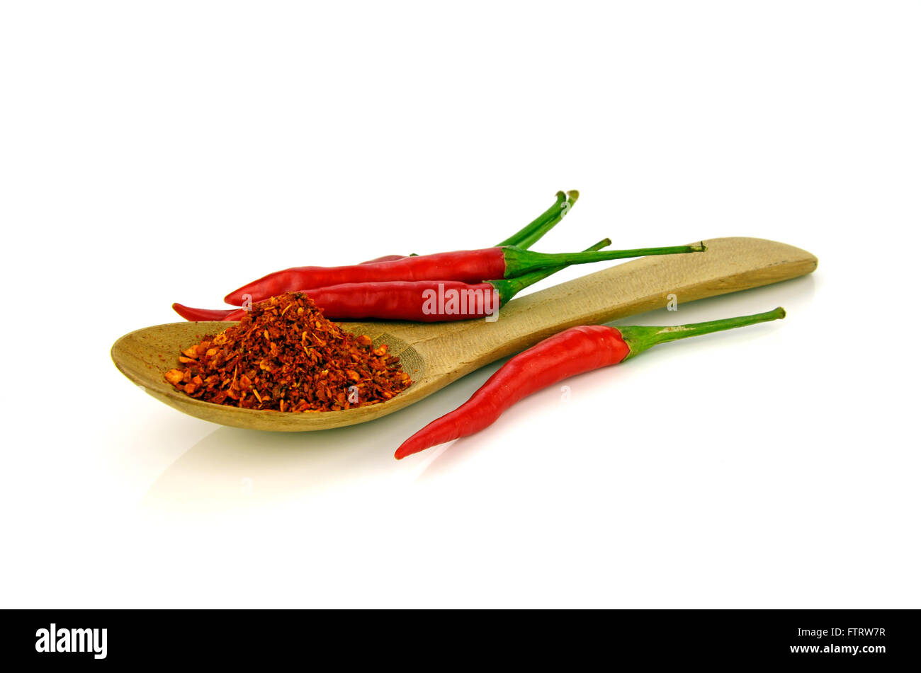 Red hot pepper chilli (Capsicum frutescens L.) with a spoon of cayenne pepper on white background. Stock Photo