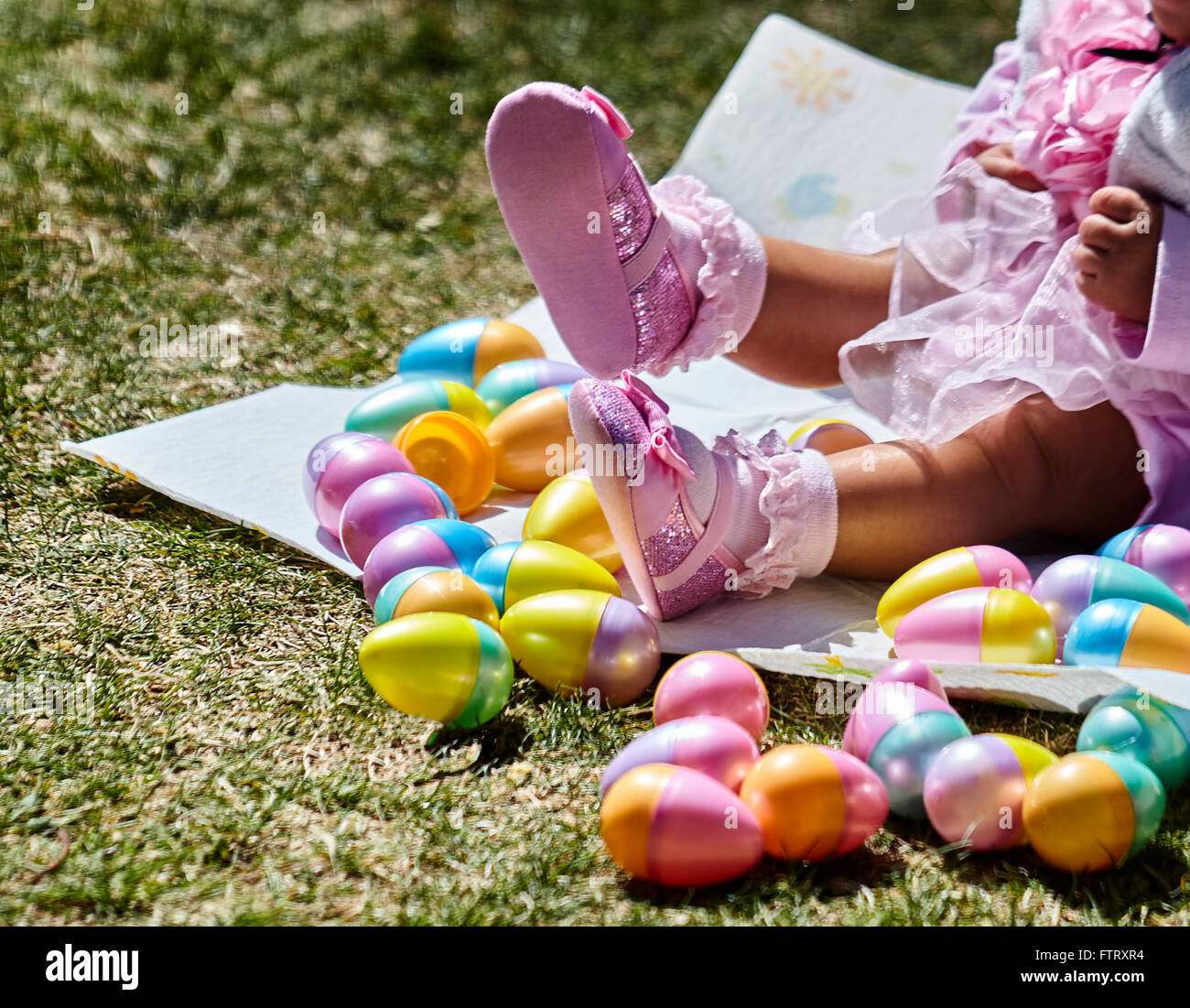 Baby girl legs with pink shoes and socks sitting in a nest of Easter