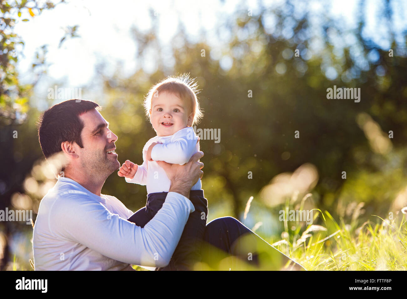 Father holding his little son, sitting on the grass Stock Photo - Alamy