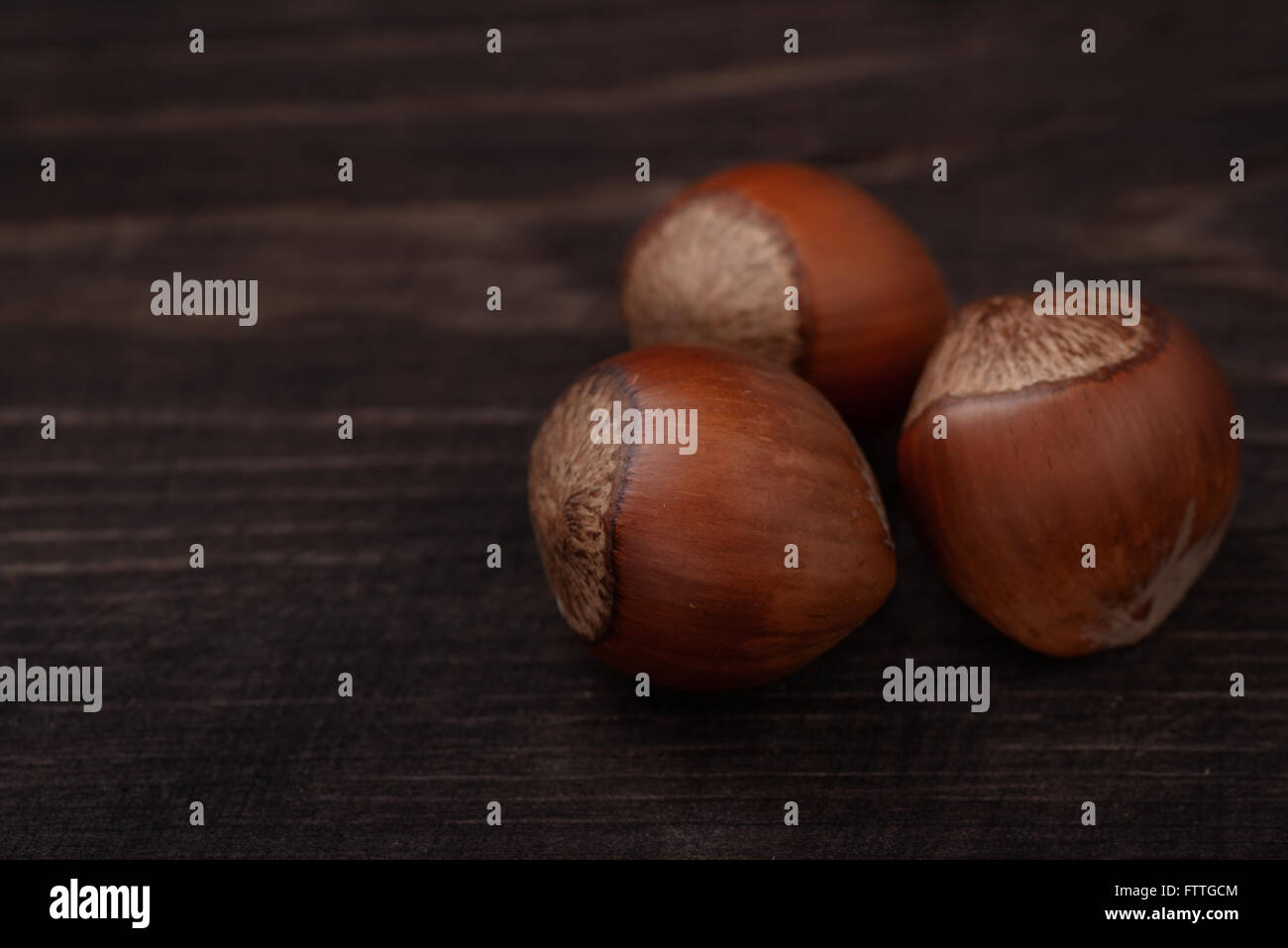 Three  hazelnuts on dark wood background Stock Photo
