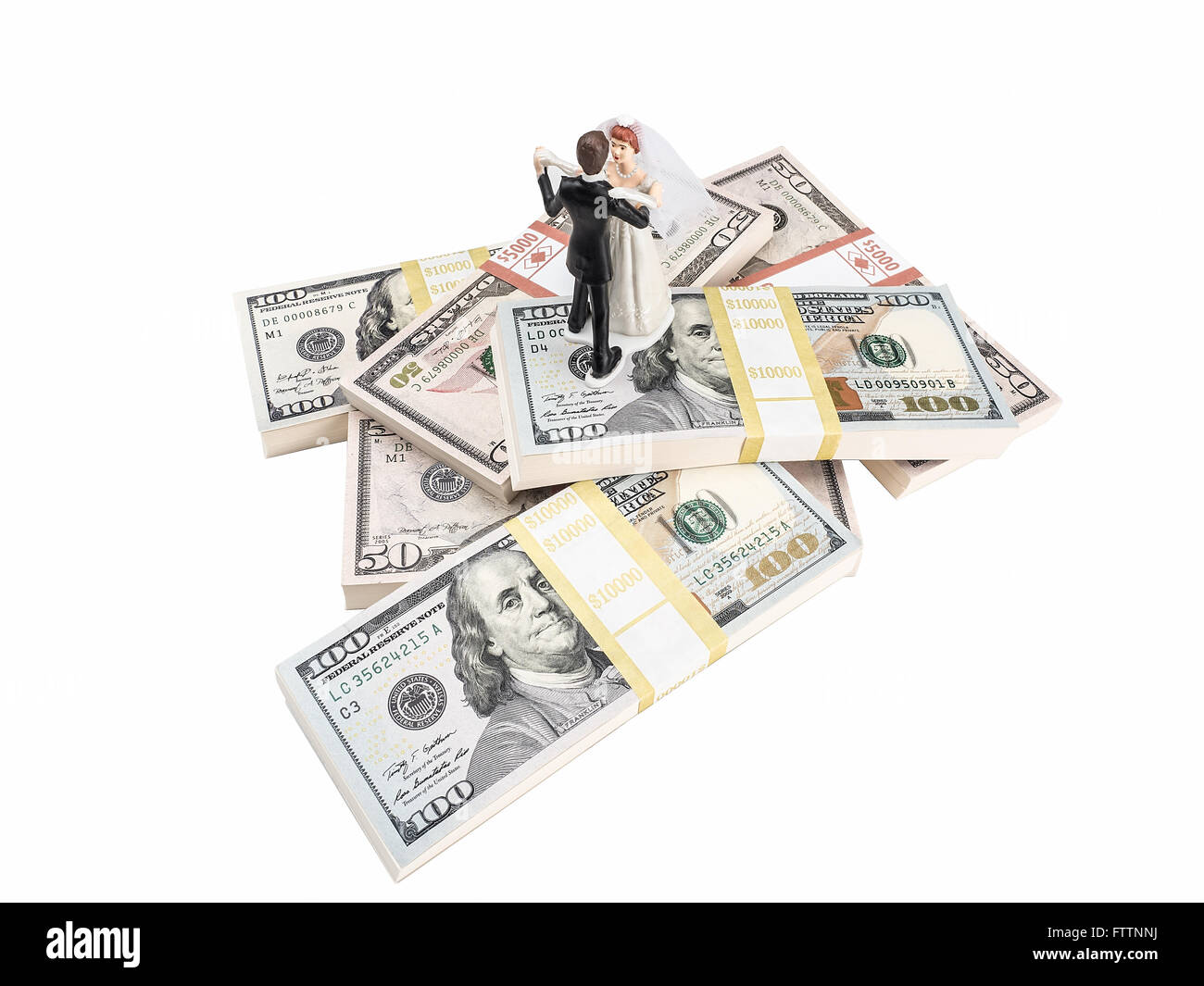 Photograph of bride and groom figurines dancing on top of stacks of U.S. paper currency, suggesting the idea of an expensive wed Stock Photo