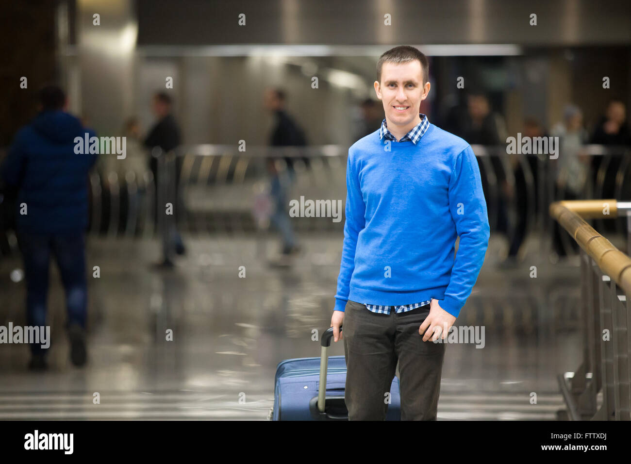 Portrait of young happy handsome travelling man wearing smart casual style clothes walking in modern airport. Cheerful guy Stock Photo