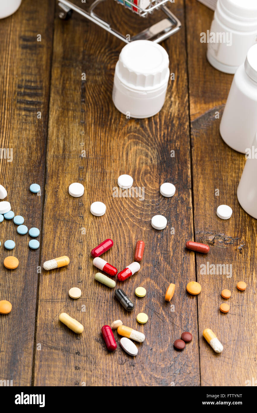Colorful pills and white pill bottles on dark wooden background.Vertical position Stock Photo