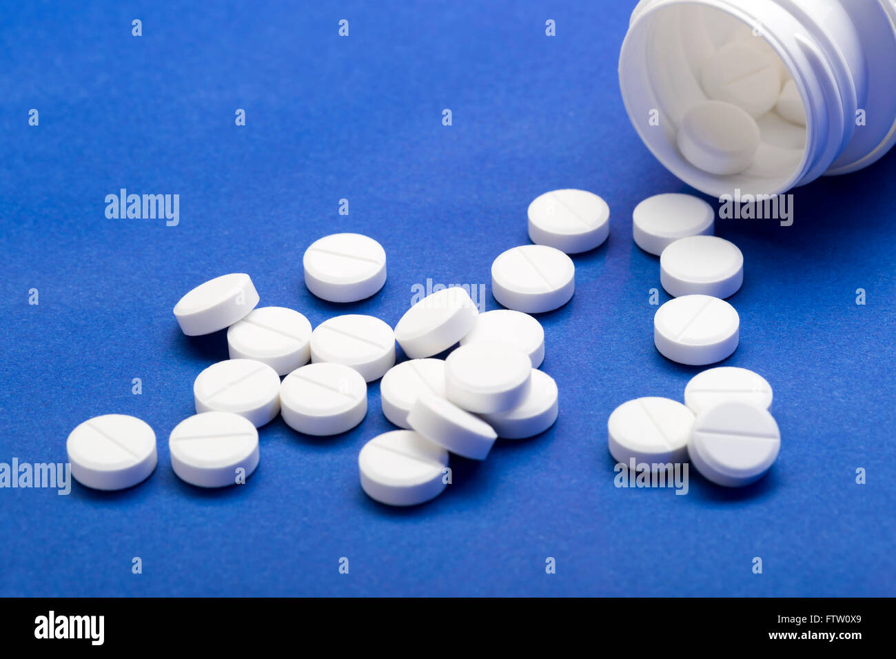 Scattered white pills of medical bottles on blue background Stock Photo
