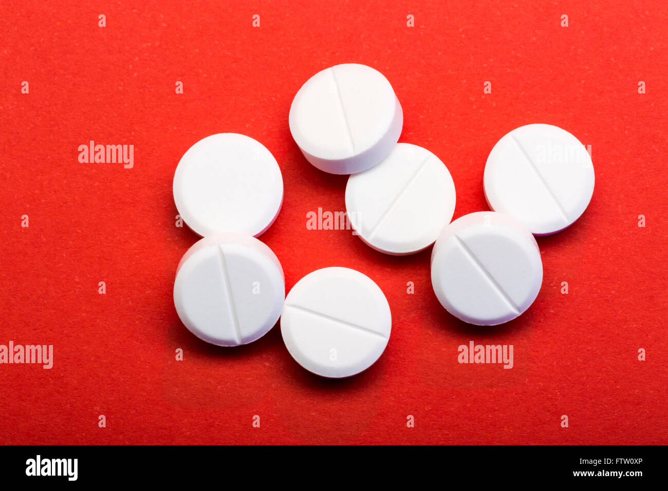 White round pills on red background. Closeup Stock Photo