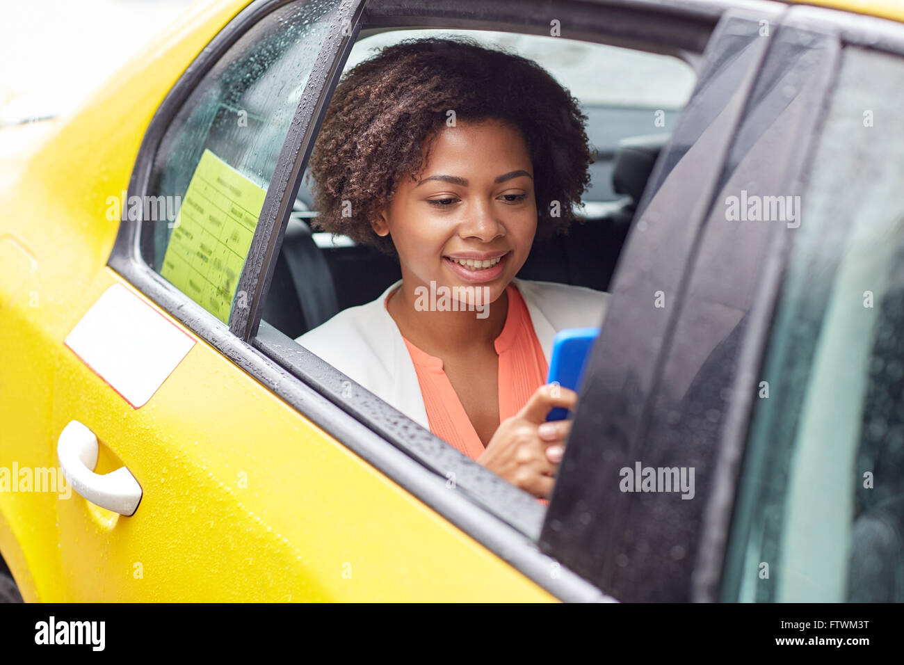 happy african woman texing on smartphone in taxi Stock Photo
