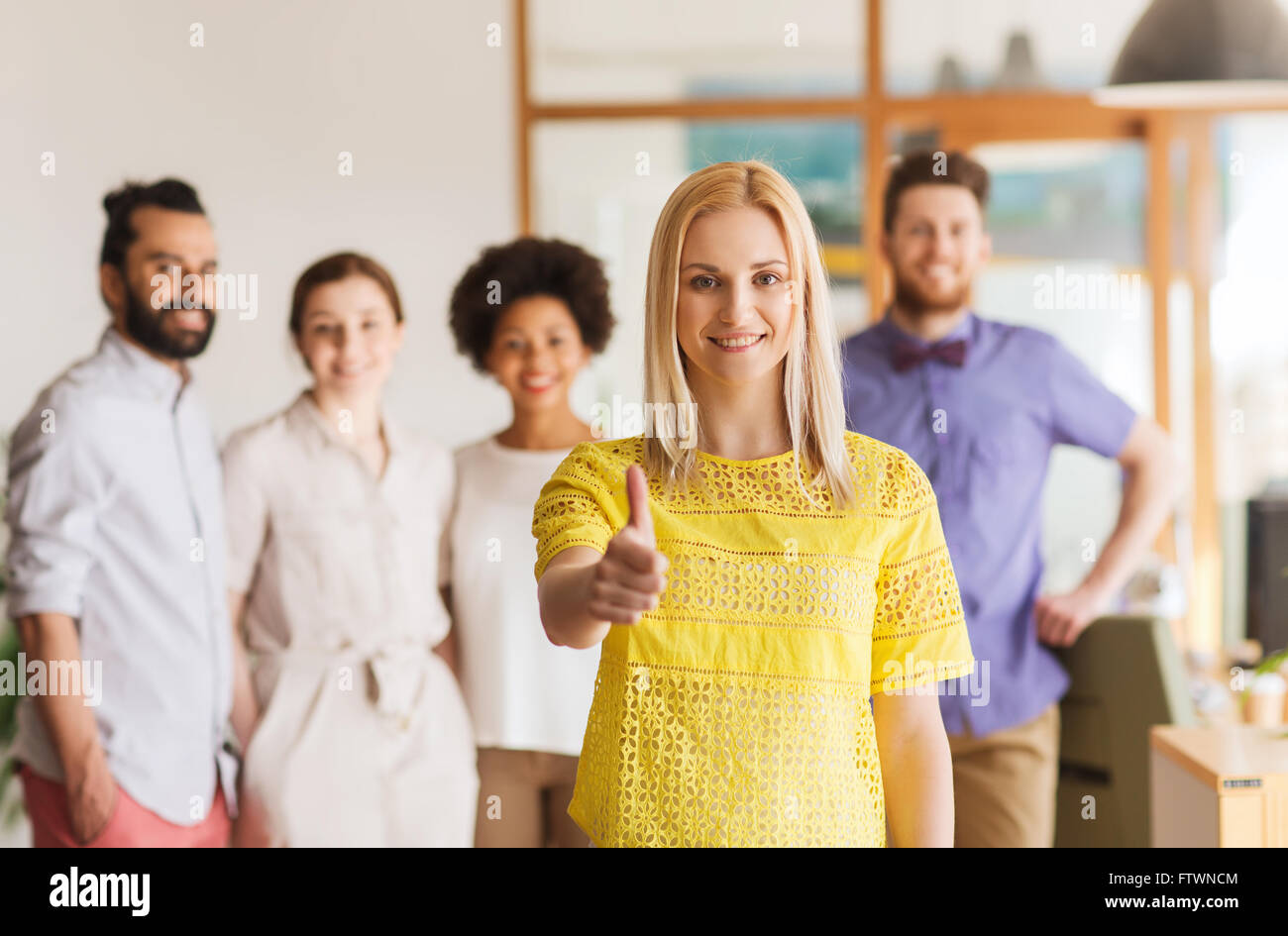 woman showing thumbs up over creative office team Stock Photo - Alamy