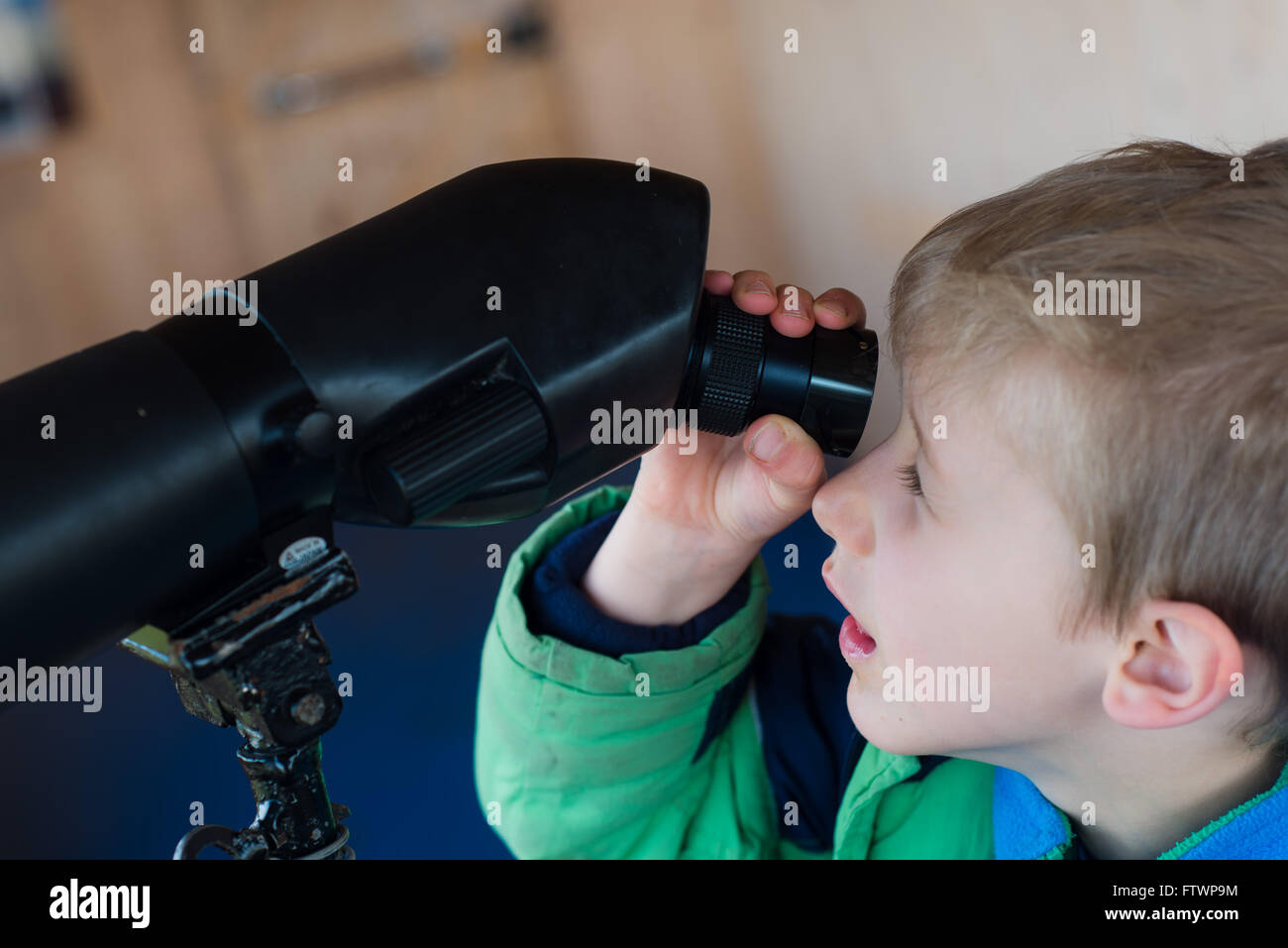 child looking out of binoculars at bird hut Stock Photo