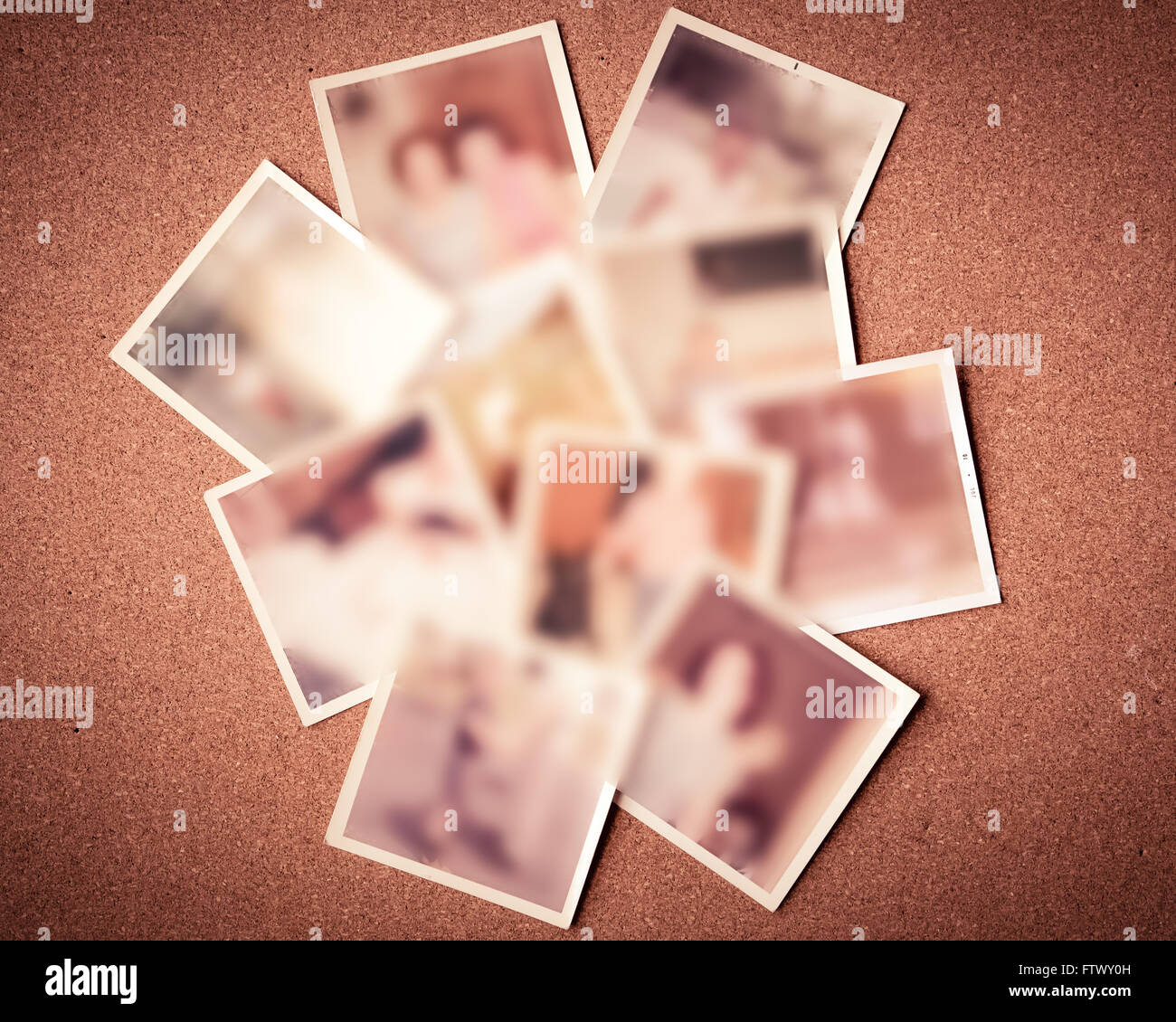 Defocused blur of scattered old family photographs against cork board Stock Photo