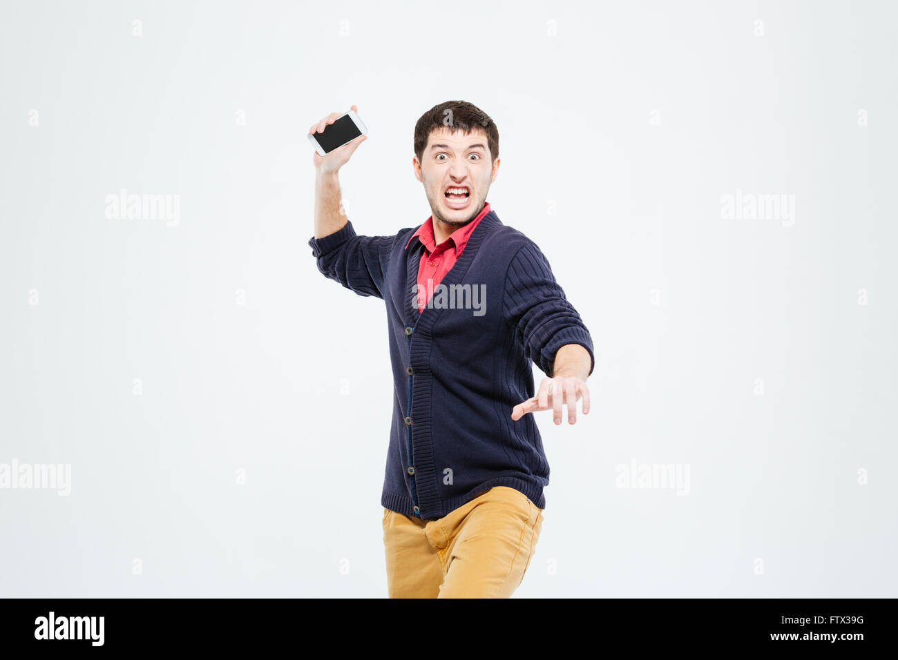 Angry man throwing phone into camera isolated on a white background
