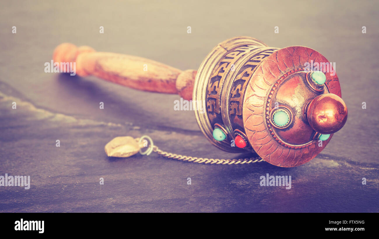 Vintage stylized old Tibetan prayer wheel used to accumulate wisdom and good karma and to purify bad karma, shallow depth of fie Stock Photo