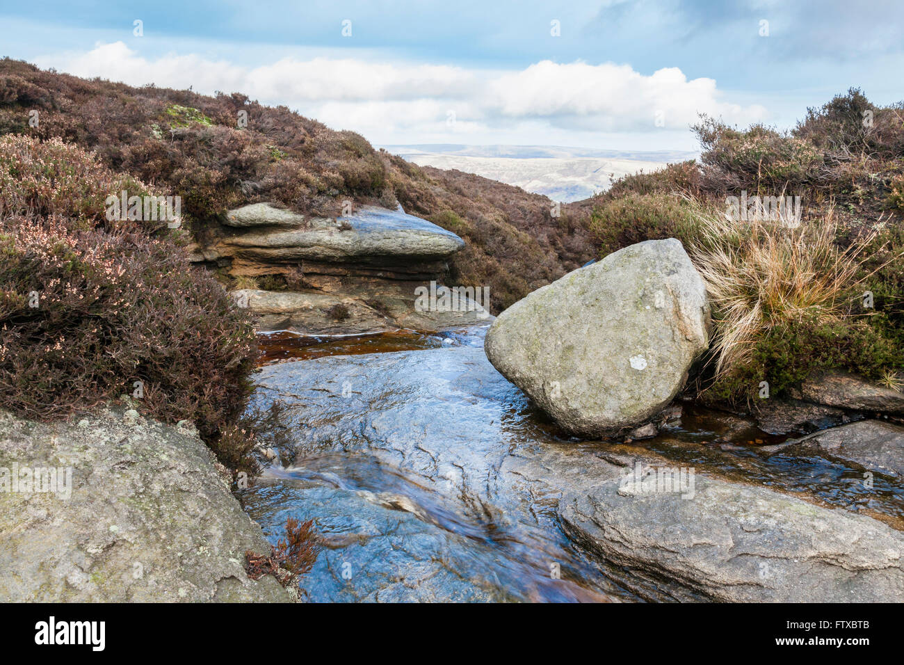 Stream flowing towards the edge of moorland on Kinder Scout, Derbyshire, Peak District National Park, England, UK Stock Photo
