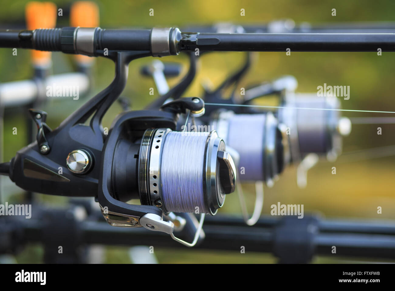 Three fishing rods with professional reel set up on support. Stock Photo