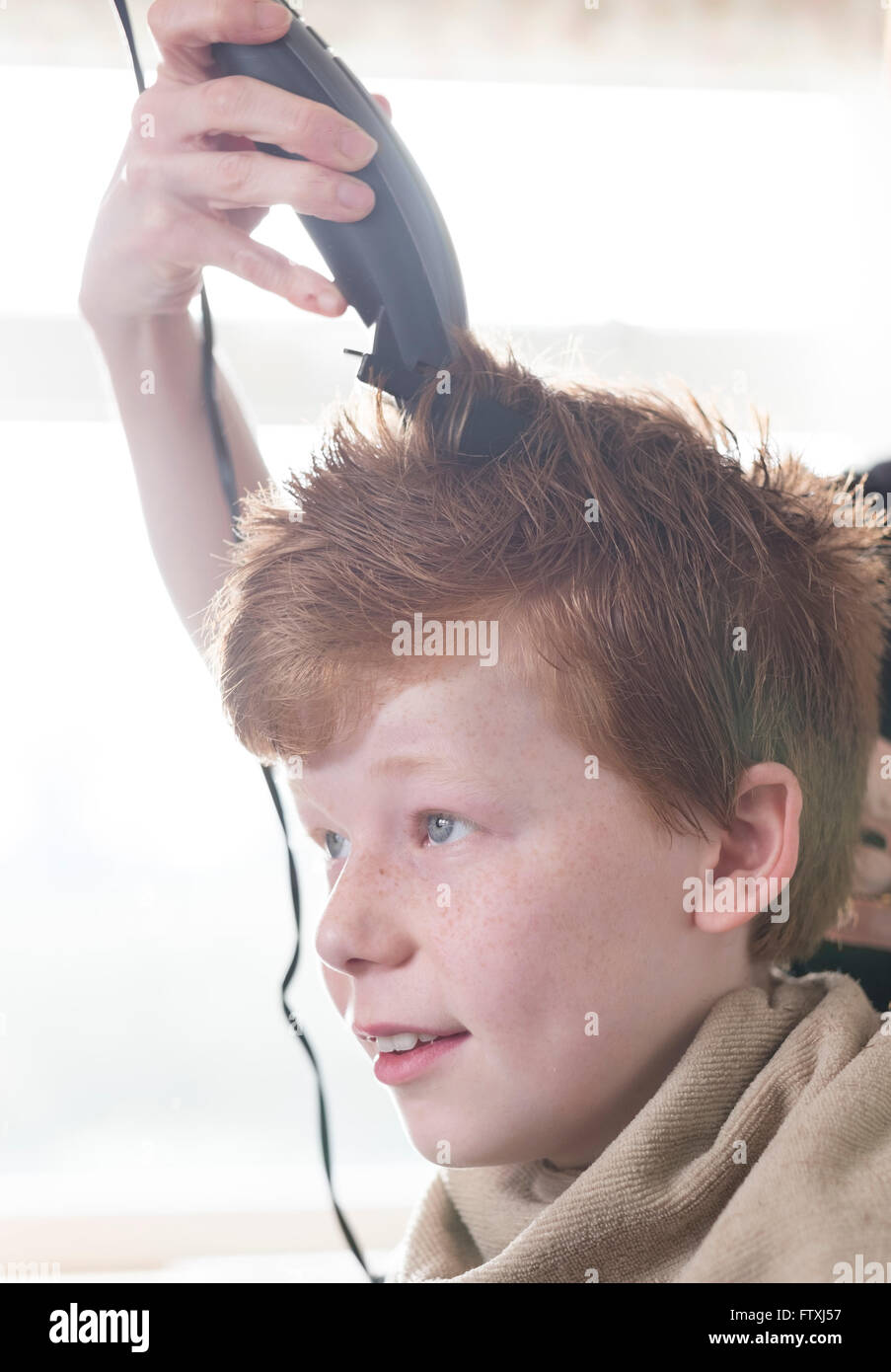 A boy having his hair cut with clippers and scissors Stock Photo Alamy