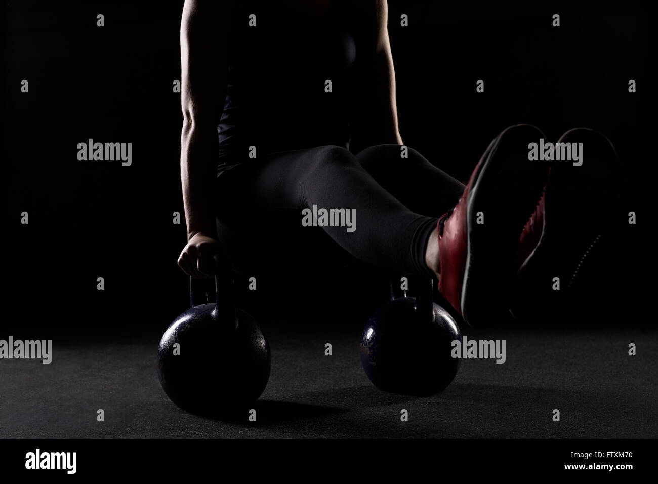Young woman strength training with kettlebells in gym Stock Photo