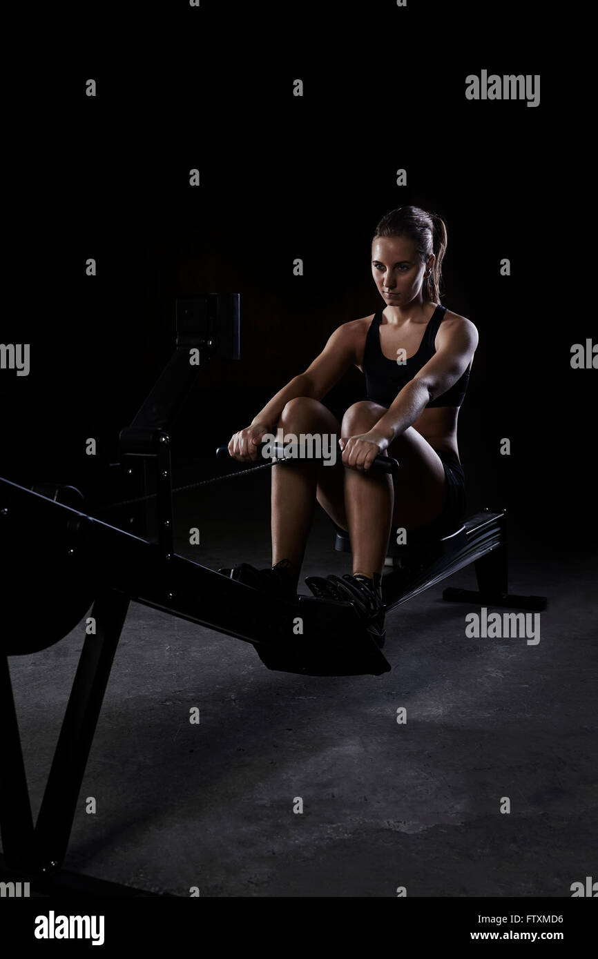 Young woman on rowing machine in gym Stock Photo