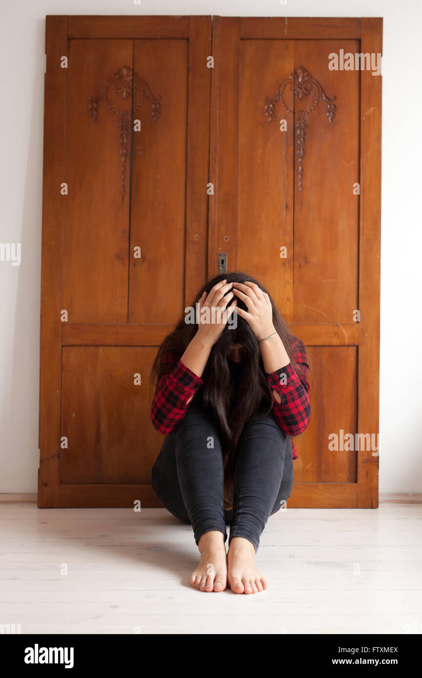 Girl sitting on floor with her  head in her hands Stock Photo