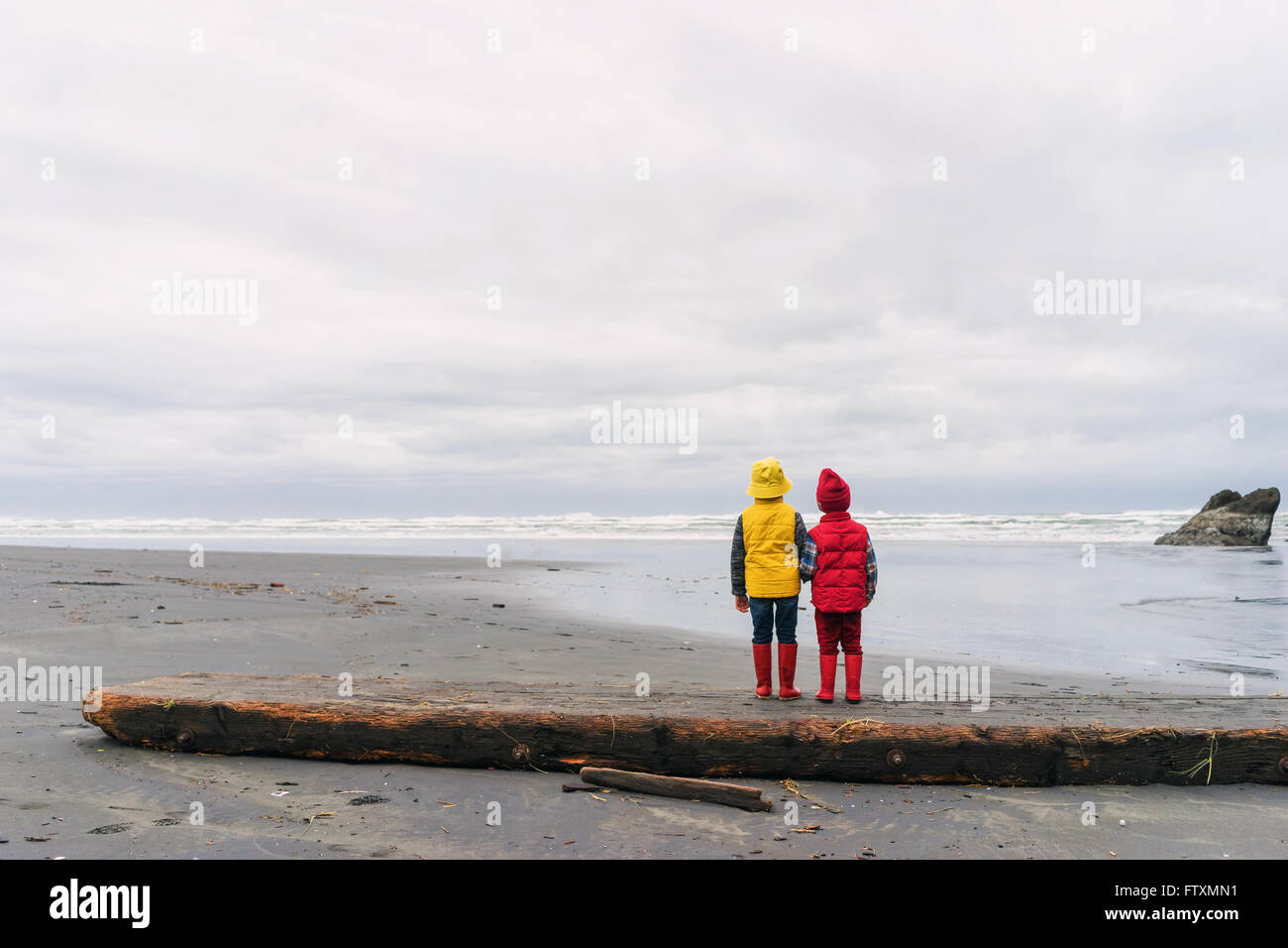 Two boys standing on beach arm in arm Stock Photo