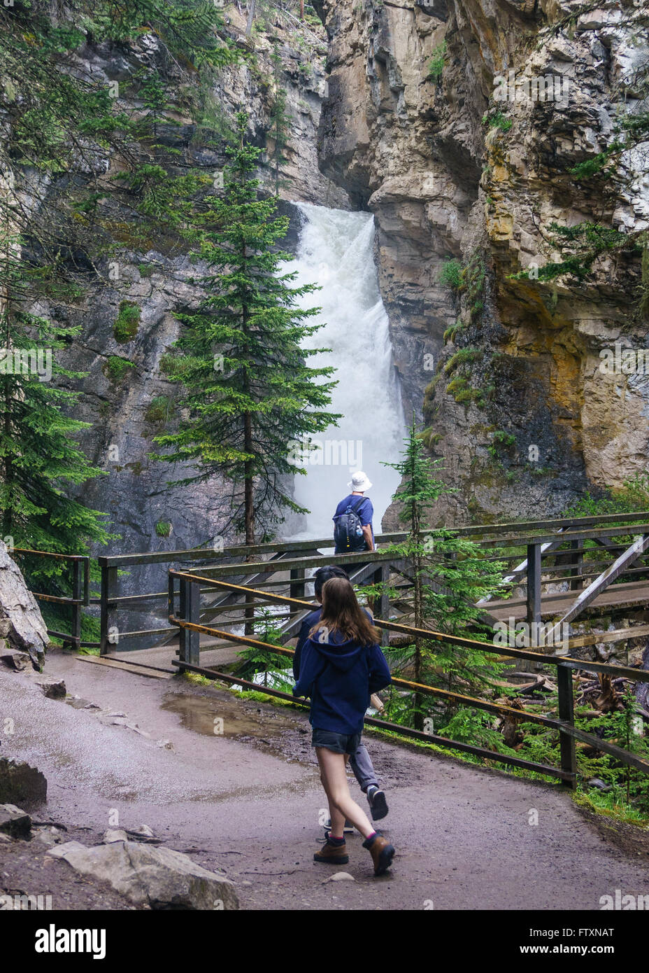 Three people approaching Johnston Canyon Lower Falls, Banff National Park, Alberta, Canada Stock Photo