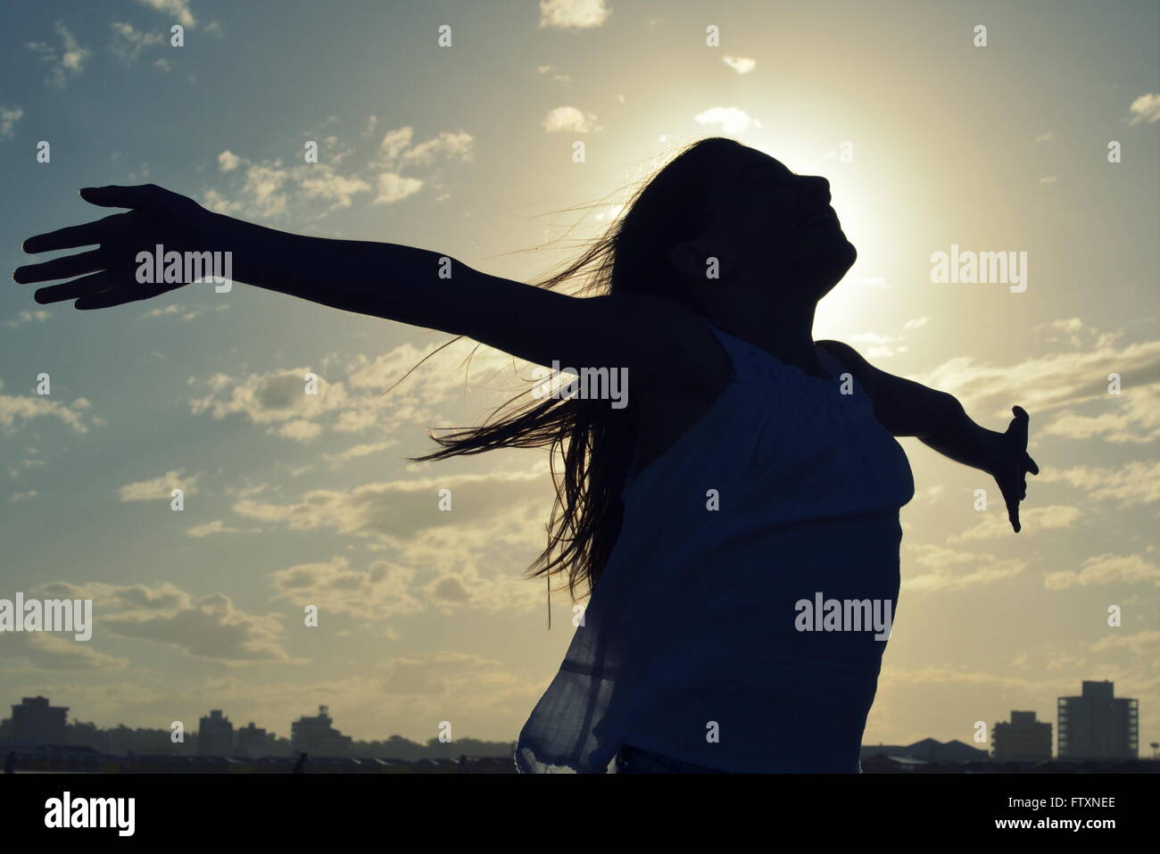 Silhouette of a girl standing with outstretched arms Stock Photo