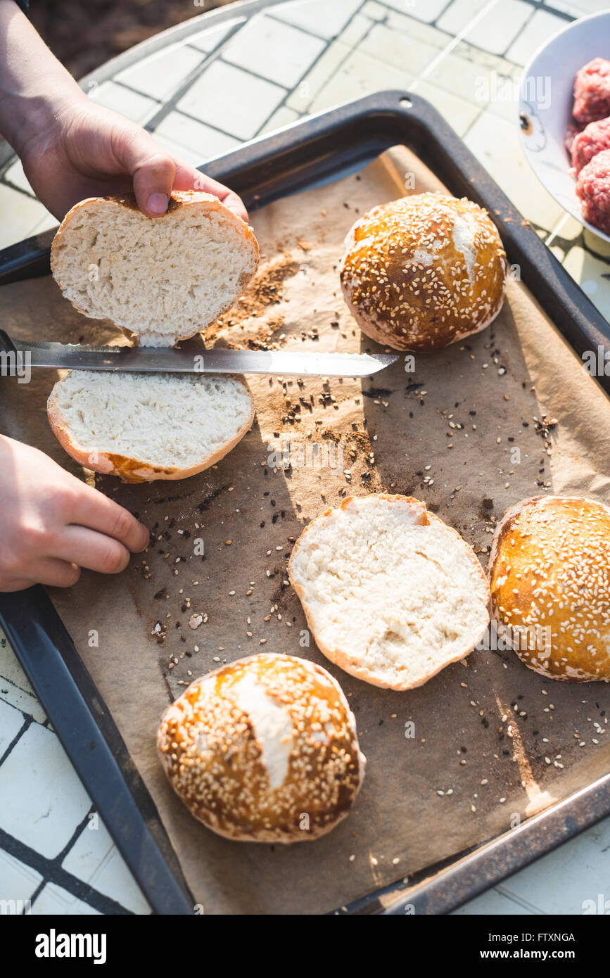 Boy cutting bread rolls in half Stock Photo