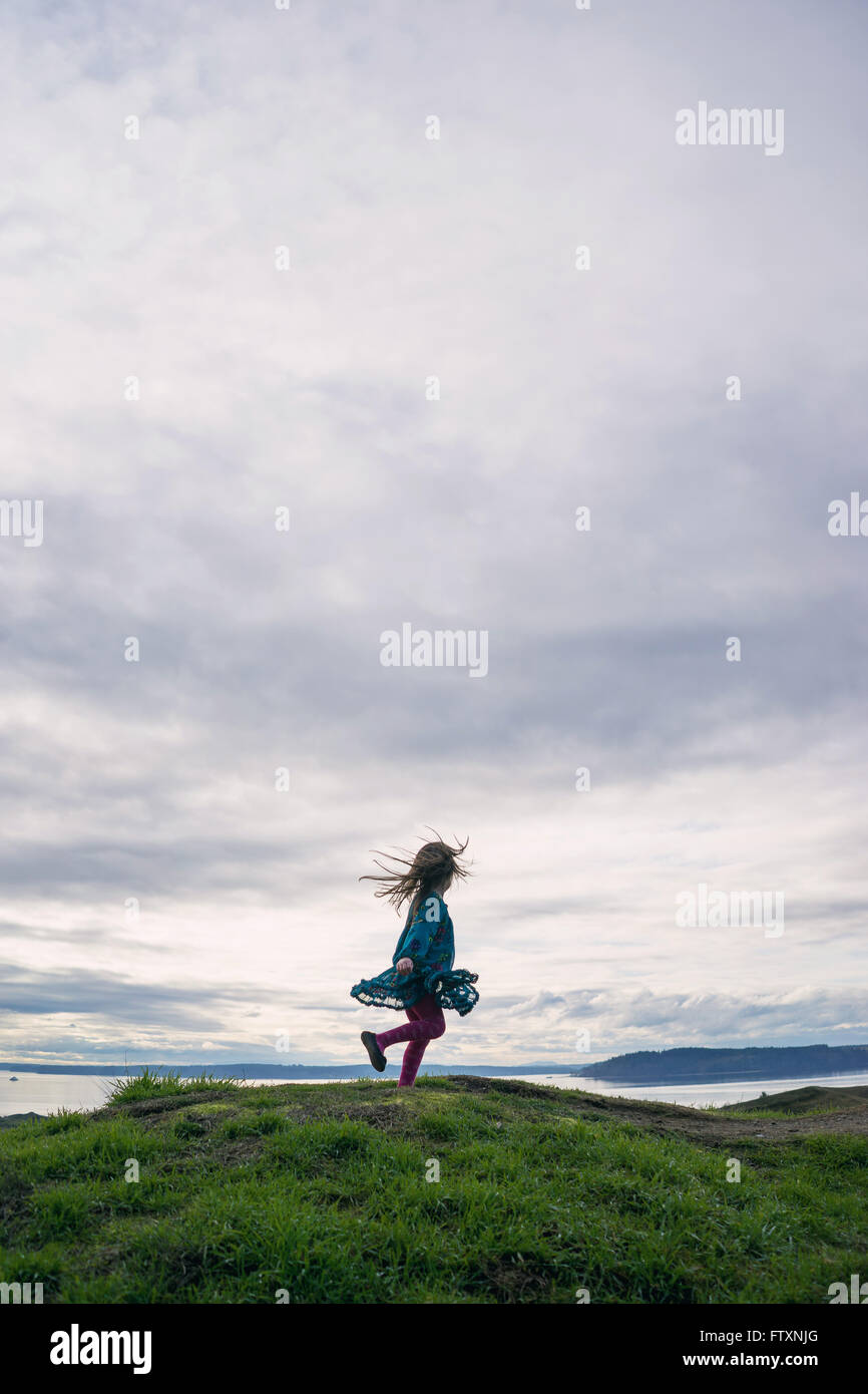 Girl spinning around on a hill Stock Photo