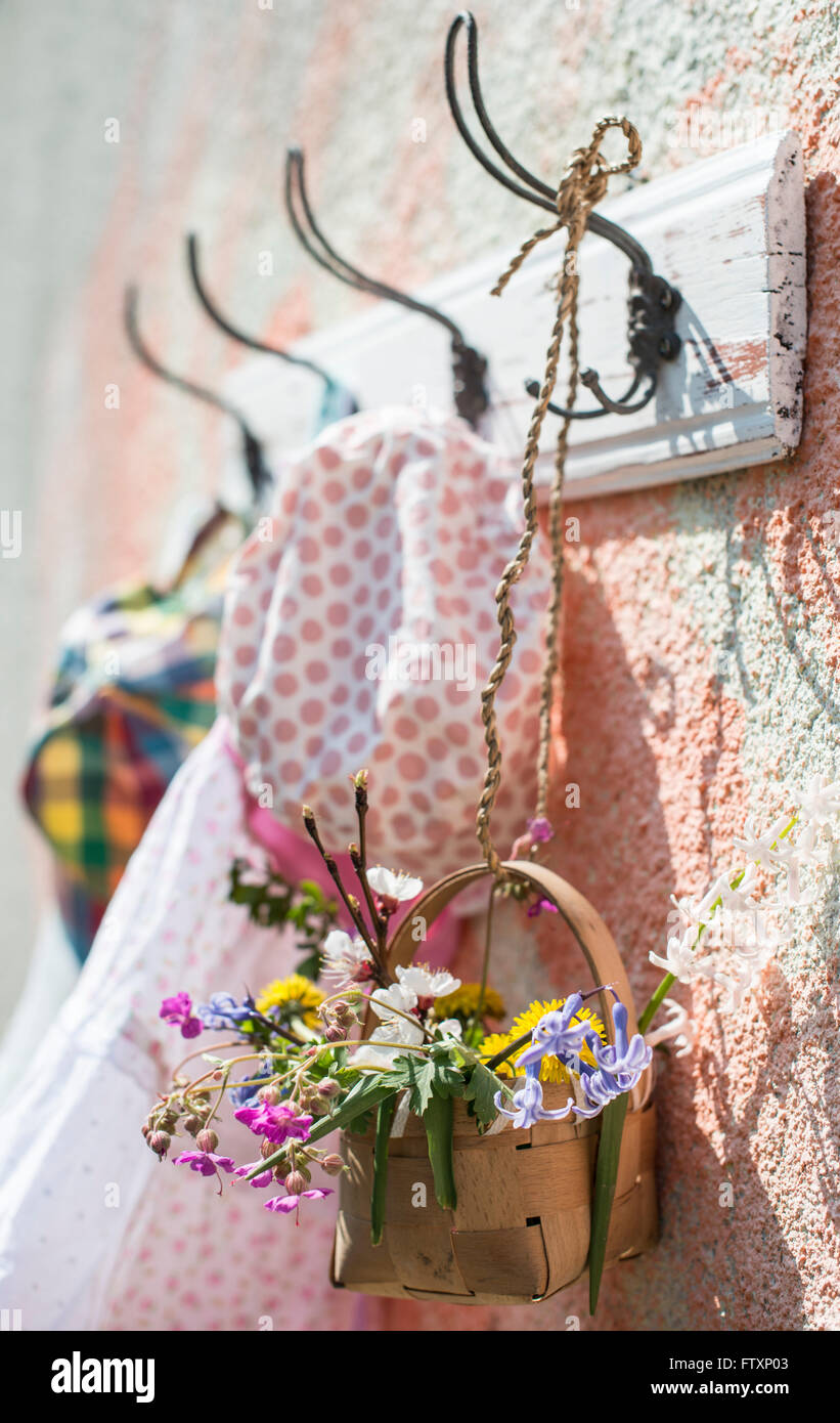 Clothes and flowers hanging on coat rack on a wall Stock Photo