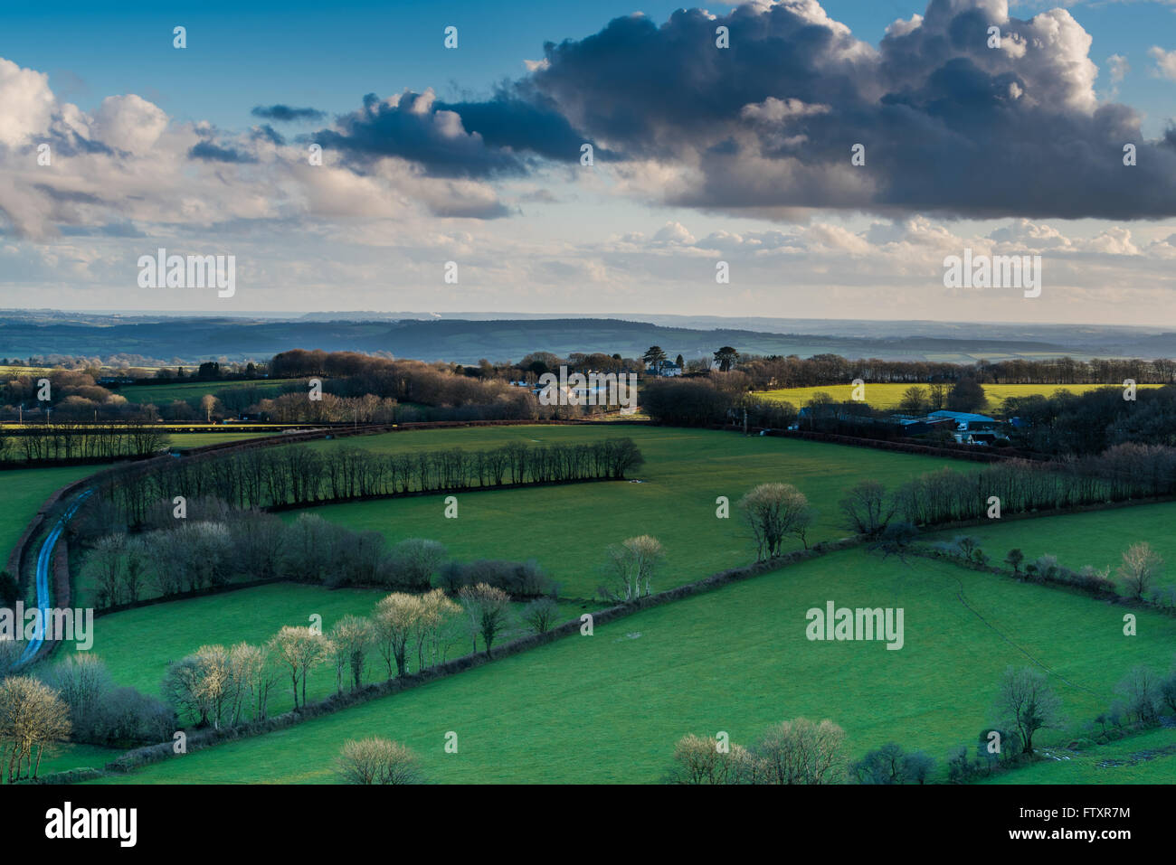 Countryside in England at sunset, view from hil top. Farmland and trees, lonely road. Stock Photo