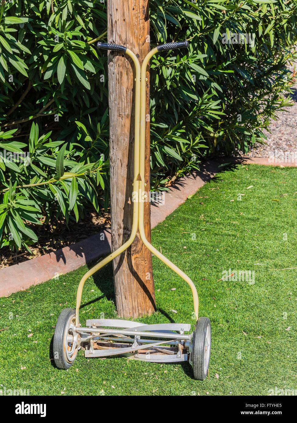 Antique reel type lawn mower leaning against a telephone pole