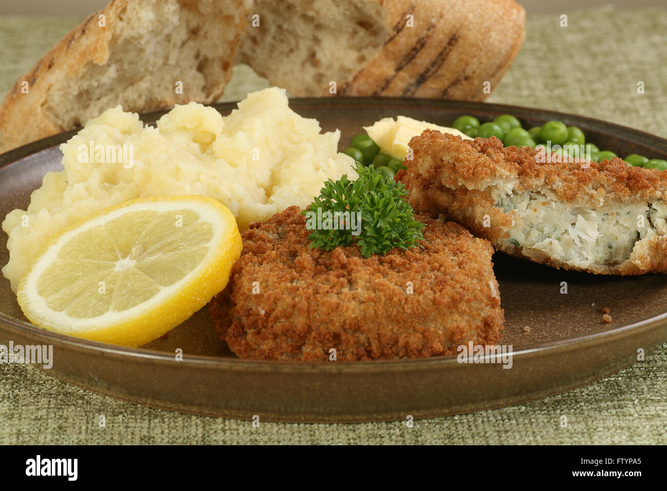 two fresh cod fishcakes with mashed potato and peas Stock Photo Alamy