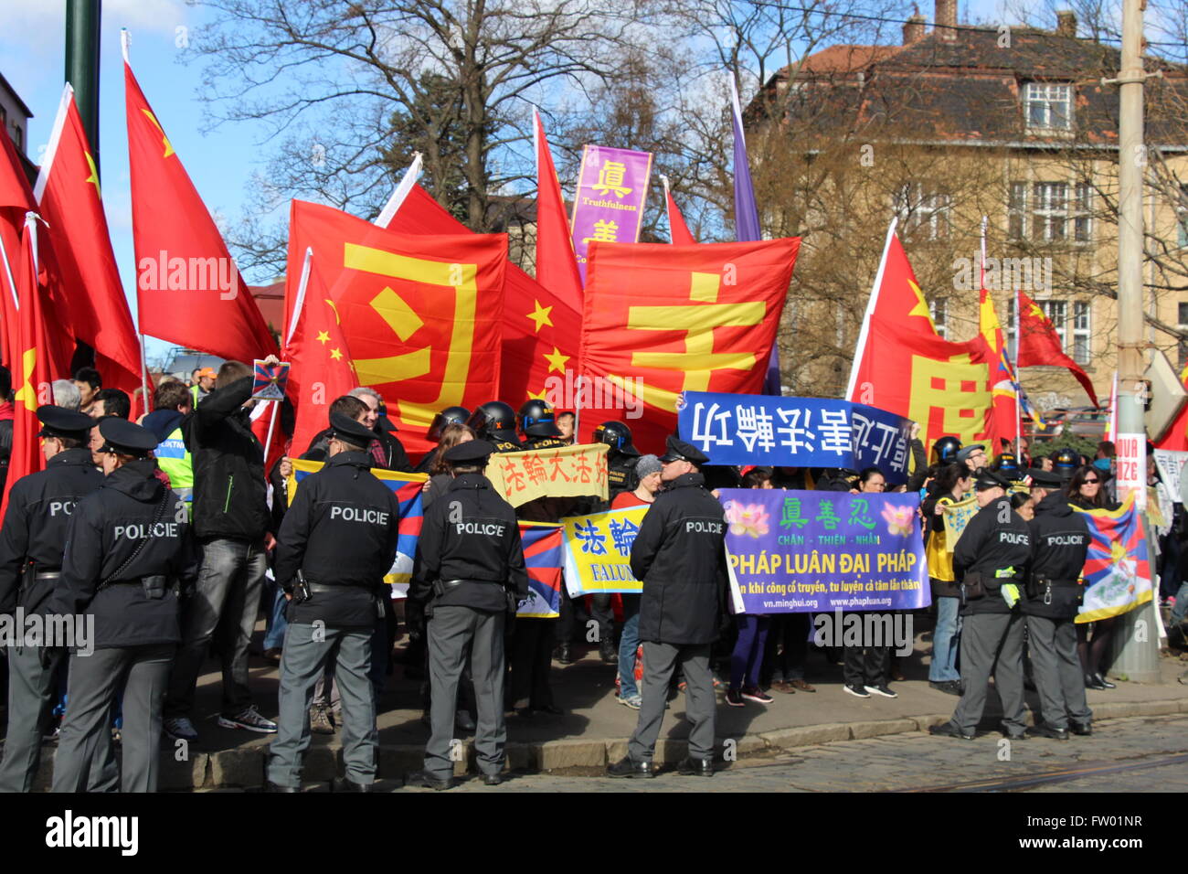 a tense situation arose on Prague's Badeniho Street where it intersects with Chodkova Street (Chodkova Street is to the left of this photograph) right on President Xi Jinping's route to Prague Castle to conduct official state business with Zeman. The flags of the People's Republic of China and corresponding banners clearly mark welcome towards Xi Jinping. However, among persons standing there are also supporters of Falun Gong, who hold up banners calling for an end to the torture and persecution of Falun Gong practitioners. Pro-Tibet protesters also. Stock Photo