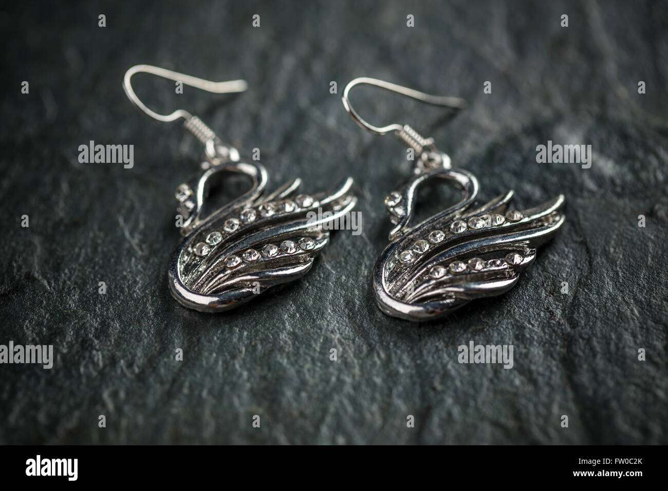 Swan shaped metal earrings on dark background Stock Photo