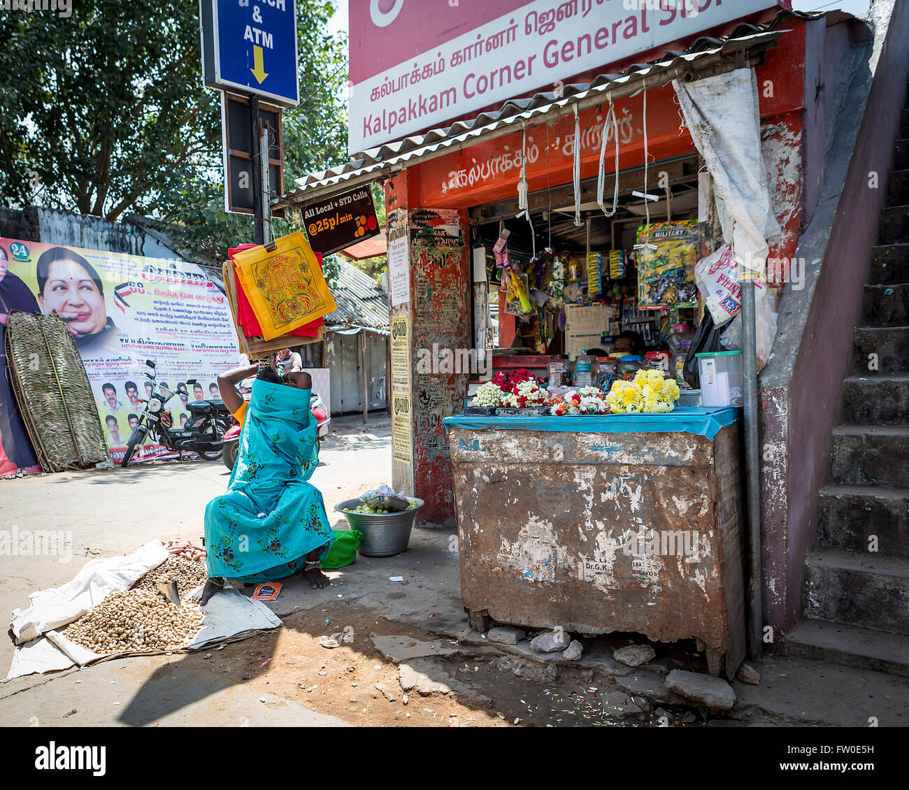 Woman selling peanuts, flowers and general goods at Kalpakkam Corner General Store, Tamil Nadu, India Stock Photo