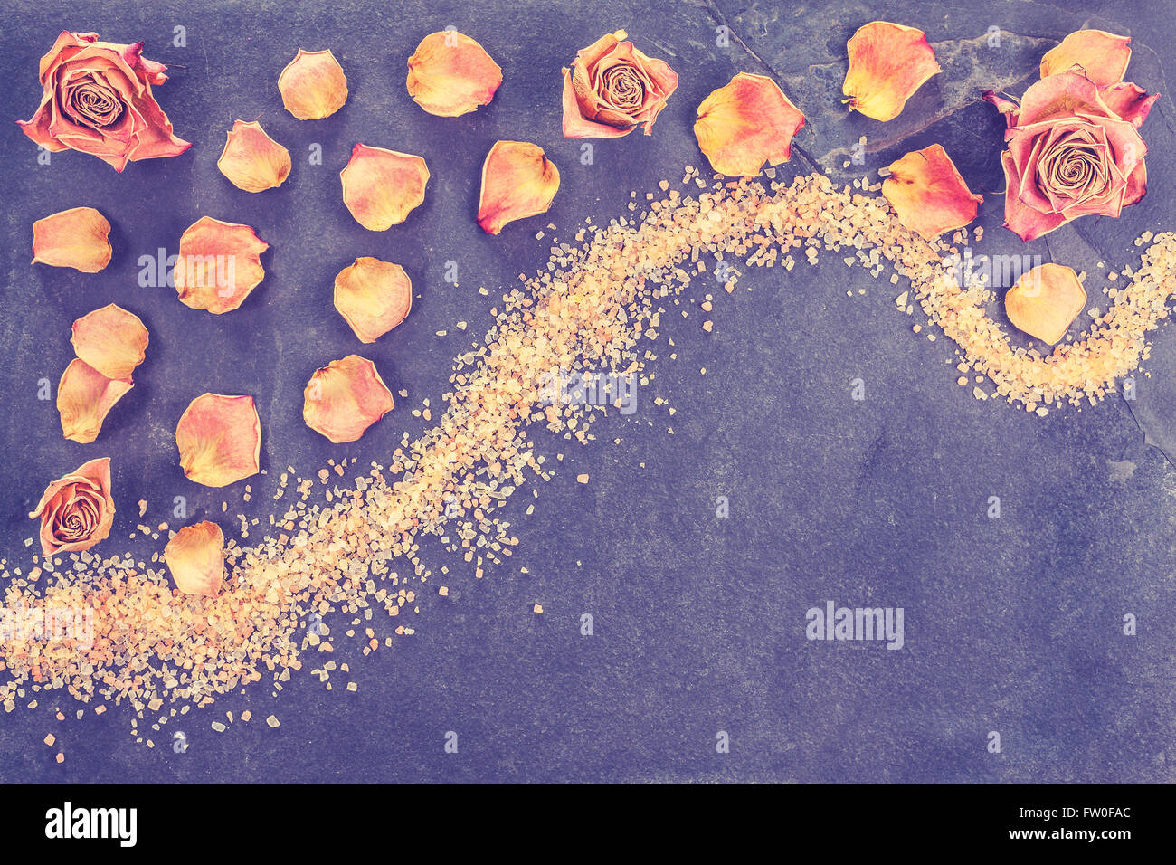 Vintage stylized dried roses and petals on slate, concept background with copy space. Stock Photo