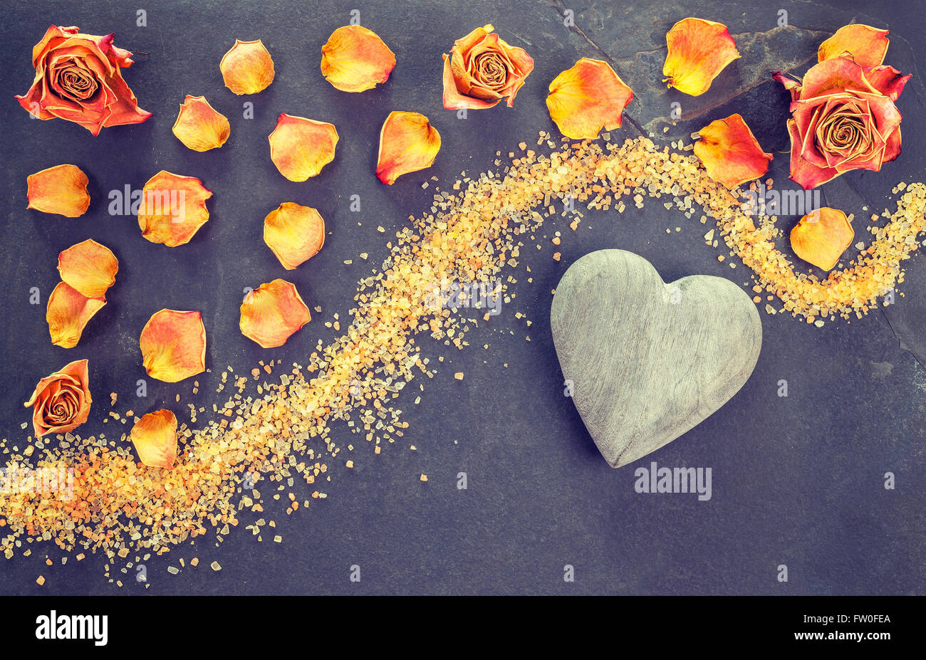 Vintage stylized dried roses and wooden heart on slate background. Stock Photo