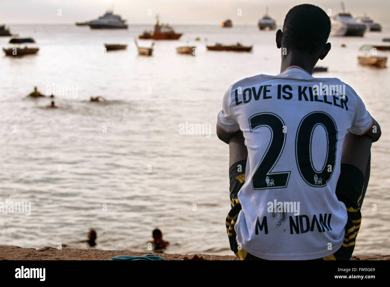 Local boy look the fishermen in the Malecon next to the pier in Stone Town, Zanzibar, Tanzania Stock Photo