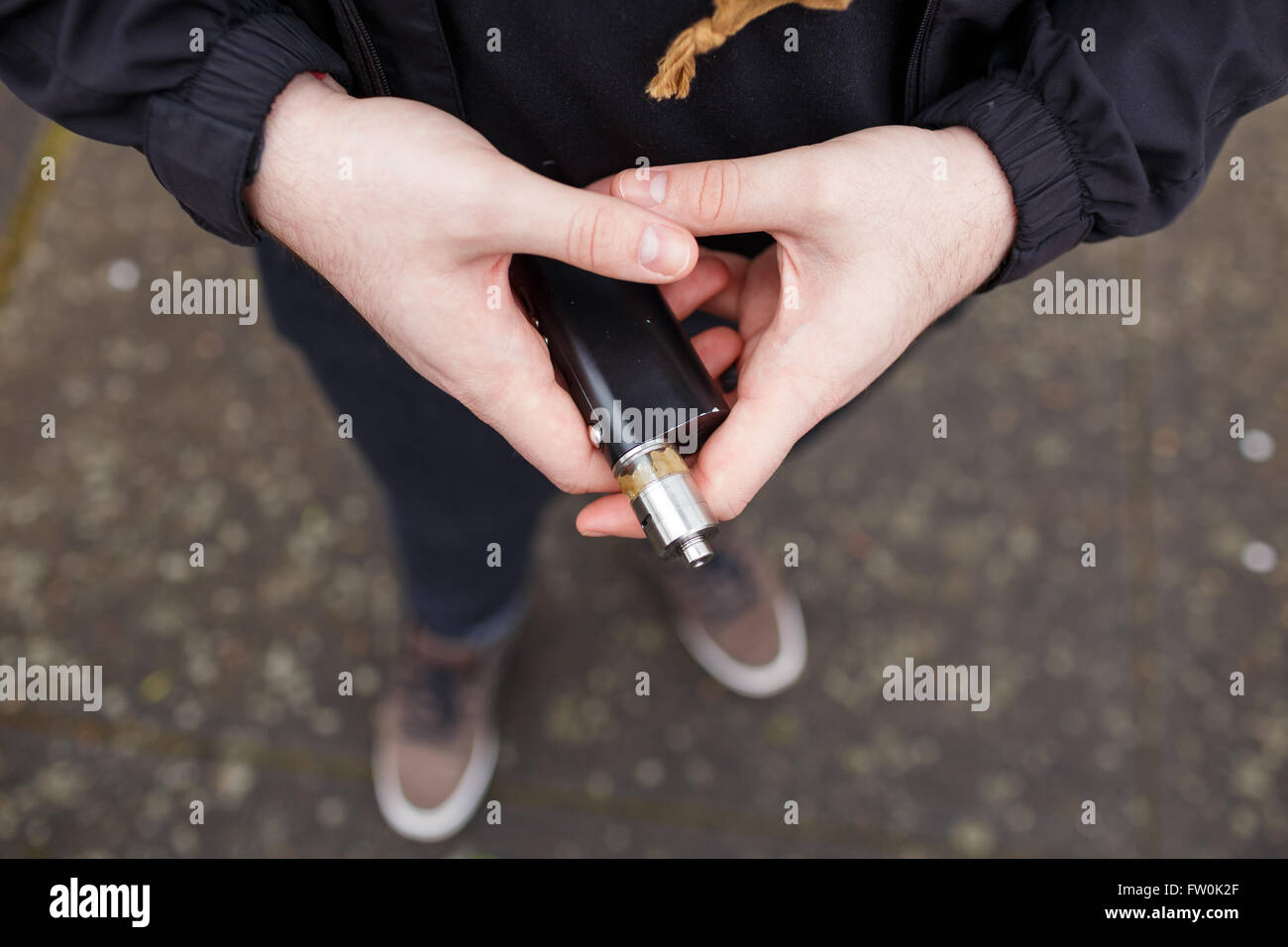 Urban lifestyle portrait of a man vaping in an urban environment with a custom vape mod device. Stock Photo