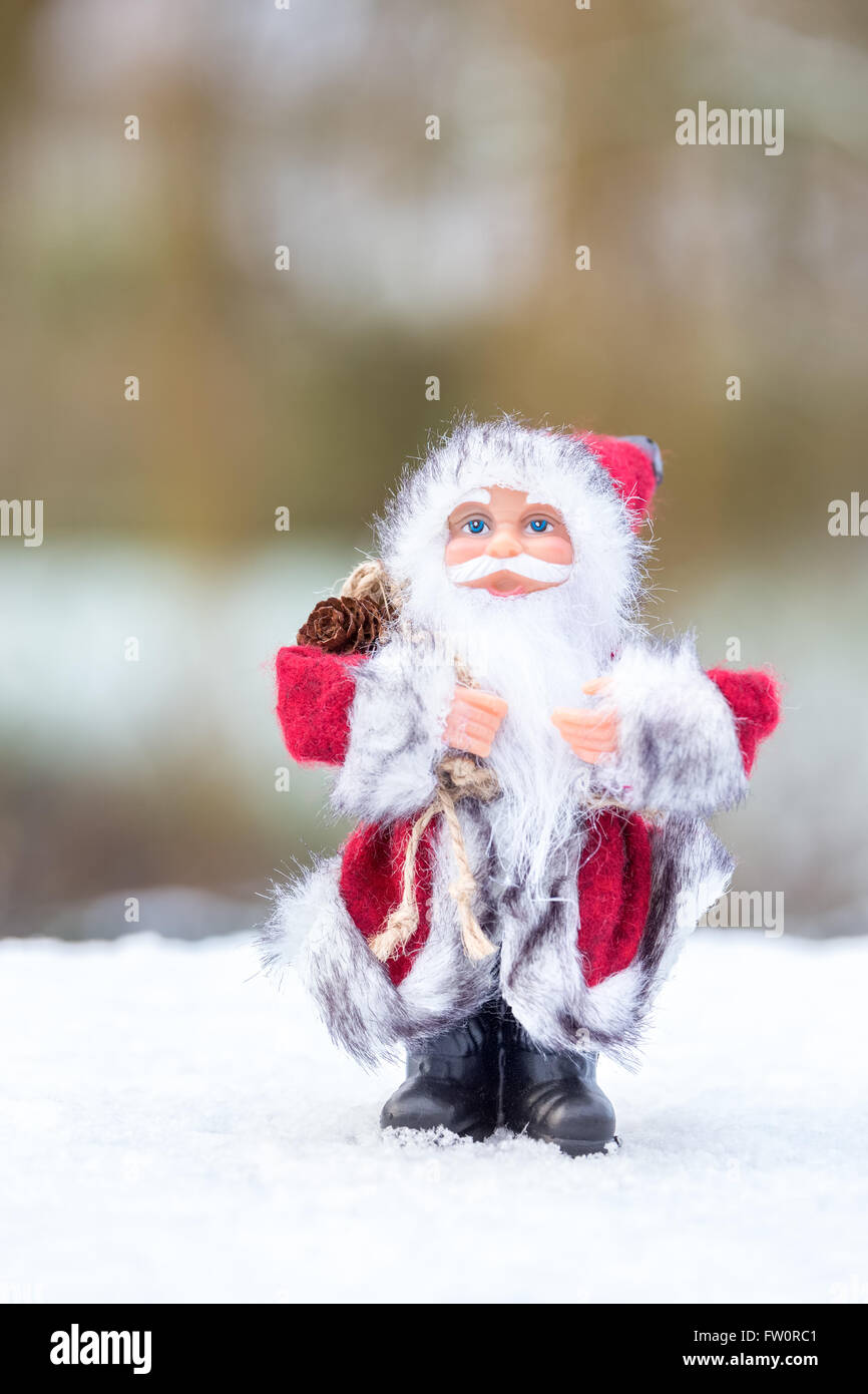 Santa Claus figurine standing in white snow outside Stock Photo