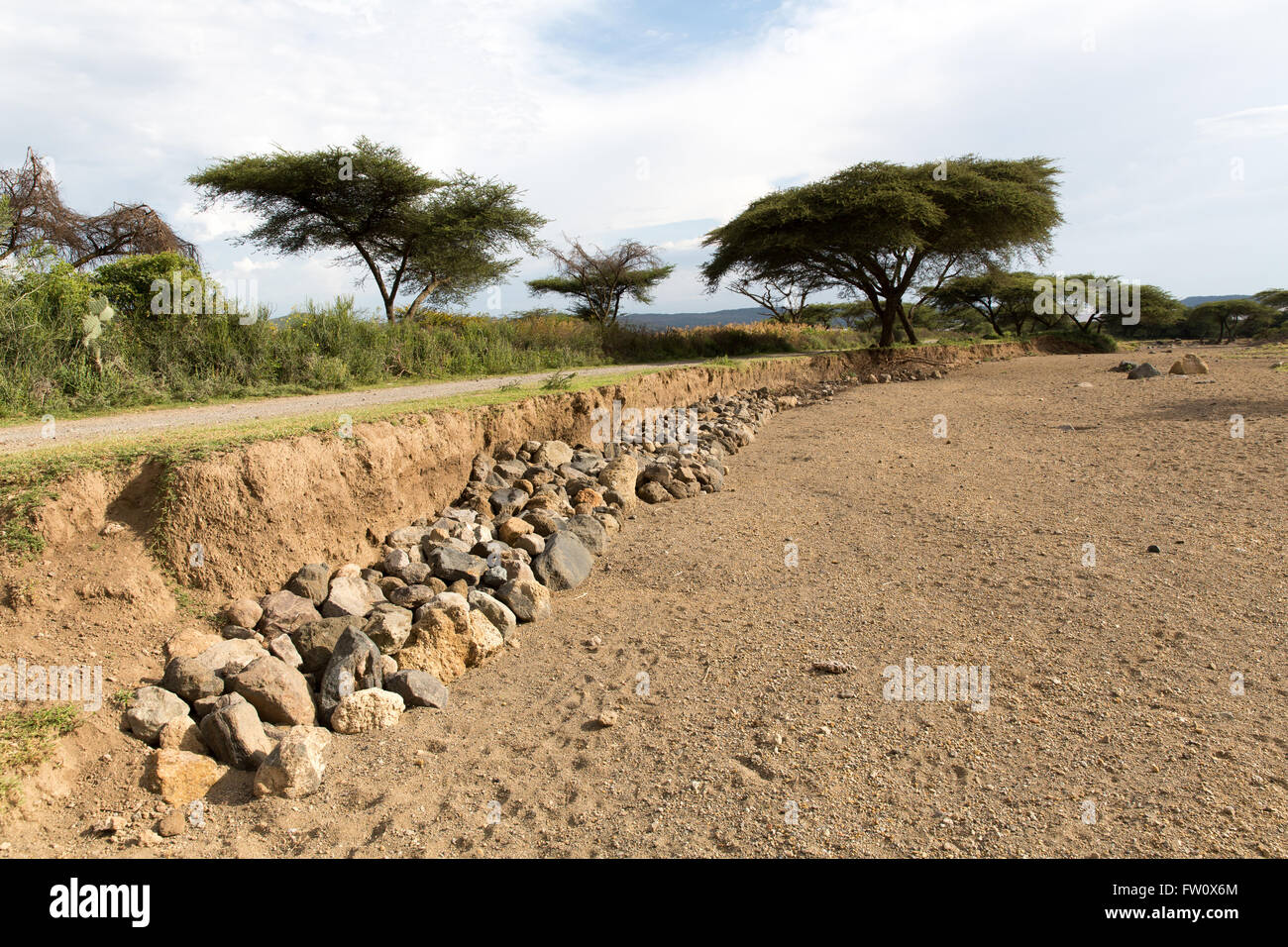 Lake Langano, Ethiopia, October 2013 Alutu Ridge – villagers have stacked stones in the riverbed to protect the road from erosion. Stock Photo